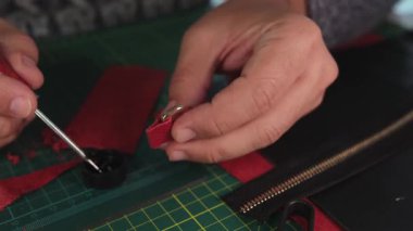 Deri ustası kırmızı deri kayışa yapıştırıcı sürüyor.
