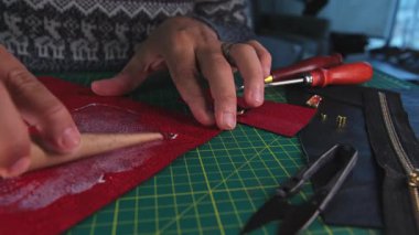 Deri ustası yapıştırıcı sürüyor ve metal düğme takıyor