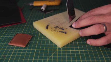 Deri ustası tezgahta deri kesiyor.