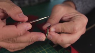 Deri ustası kırmızı deri bir parçaya yapıştırıcı sürüyor.