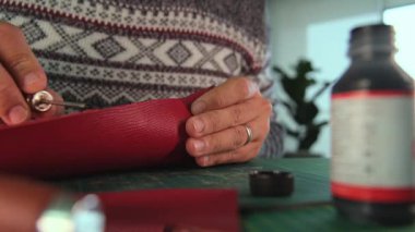 Deri ustası kırmızı deriye boyayı sürüyor.