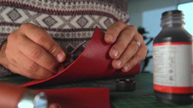 Deri işçisi kırmızı deri üzerinde çalışıyor.