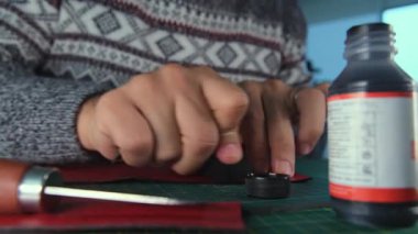 Deri ustası kırmızı deriye boyayı uyguluyor.