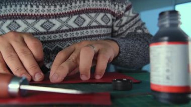 Deri işçisi kırmızı deri üzerinde çalışıyor.