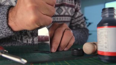 Deri bir zanaatkar deri bir cüzdanın kenarını yakıyor.
