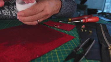 Deri ustası kırmızı deriye yapıştırıcı sürüyor.