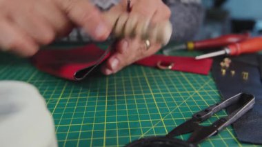 Siyah deriyle çalışan bir zanaatkar kesim hasırının üzerinde bir aletle