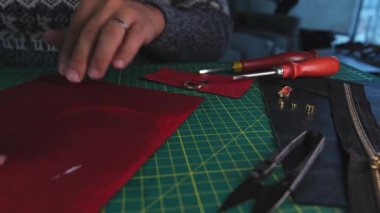 Zanaatkar ahşap bir aletle kırmızı deri üzerinde çalışıyor.