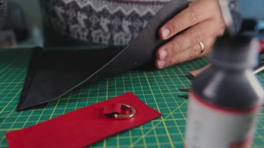 Zanaatkar tezgahın üzerine kırmızı ve siyah deri parçaları yapıştırıyor.
