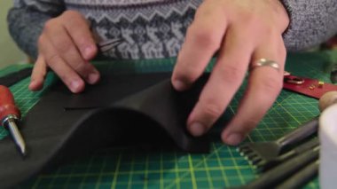 Deri ustası siyah deriyi makasla kesiyor.