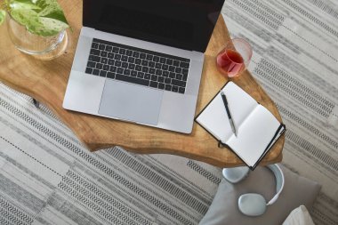 Uzak çalışma ve serbest yaşam tarzı için ideal, ahşap bir masa üzerinde dizüstü bilgisayar, bitkiler ve defter içeren modern ofis kurulumu