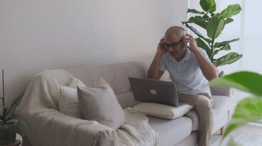 İşadamı evde dizüstü bilgisayarla çalışıyor ve kulaklık takıyor.