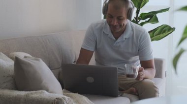 Evden bilgisayarla ve kahveyle uzaktan çalışan odaklanmış bir çalışan.