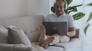 Rahatlamış bir adam oturma odasından çalışıyor, bir fincan kahvenin tadını çıkarıyor.