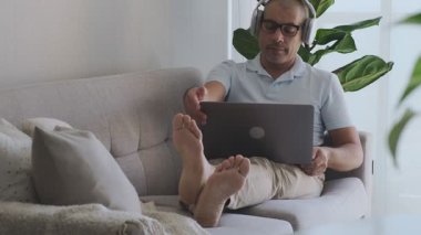 Ev bilgisayarında çalışan kulaklık takan serbest çalışan biri.