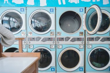 Açık mavi sanayi kurutma makineleri bir sonraki çamaşır yükünü self-servis çamaşırhanesinde bekliyor.