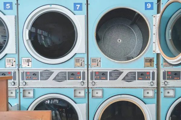 Açık mavi sanayi kurutma makineleri bir sonraki çamaşır yükünü self-servis çamaşırhanesinde bekliyor.