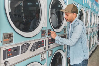 Müşteri çamaşırhanedeki çamaşır makinesine bozuk para yerleştiriyor.