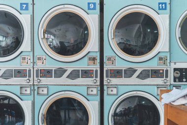 Açık mavi sanayi kurutma makineleri bir sonraki çamaşır yükünü self-servis çamaşırhanesinde bekliyor.