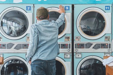 Çamaşırhanede günlük çamaşırlarını yıkayan bir adam.