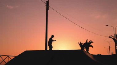Gün batımında bir patencinin silueti numaralar yapıyor. tanınabilir değil.