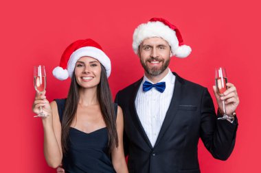 Mutlu Noel Baba çifti için kurumsal Noel partisi. Stüdyodaki Noel Baba çifte mutlu Noeller. Noel Baba çifti için Noel kutlaması. Noel Baba şapkalı çift şampanyayı kırmızıda izole ediyor..
