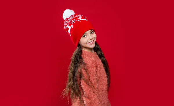 赤い背景に孤立した帽子の幸せな10代の子供 スタジオでは10代の子供がセーターと帽子を着ています 10代の子供の冬のファッション 帽子のニットウェア 帽子の10代の子供モデル — ストック写真