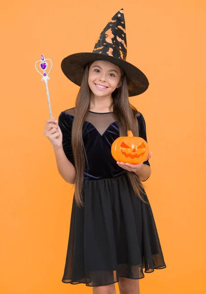 happy witch child with magic wand and pumpkin jack o lantern wear costume of wizard on halloween party, halloween miracle.