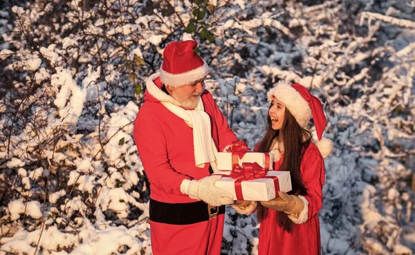 给圣诞老人的美丽的多雪的冬天 孩子和老人准备庆祝节日 寒假和假期 爷爷穿着桑塔服装和小女孩在一起 户外送礼的圣诞老人助手 — 图库照片