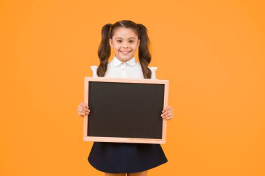 Küçük reklam yapımcısı. Küçük bir okul çocuğu sarı arka planda tahta tutuyor. Okul reklamı için siyah tahtası olan küçük çocuk. Metin için boş tebeşir tahtası ile küçük kız, boşluk kopyalamak.