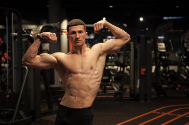 Kaslı gövdeli güçlü bir adam. Kol kasları kaslı. Spor salonunda çift kol kasları var..