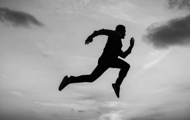 Acele et. Günlük motivasyon. Hayatın ve doğanın tadını çıkarıyor. İş başarısı. Özgürlük. Kişisel başarı hedefi. Gökyüzü arka planında çalışan enerjik bir koşucu silueti. Kendine güvenen iş adamı.