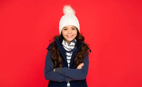 冬季时尚 一个快乐的孩子 卷曲的头发 头戴帽子 手握双手 红底少女 穿着保暖衣服的孩子的肖像 表达积极的情绪 — 图库照片