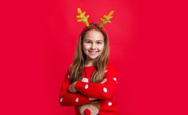 圣诞节时 积极的少女穿着毛衣和鹿角 快乐的圣诞节 穿着红色圣诞背景鹿角的滑稽少女 在鹿角的圣诞少女 — 图库照片