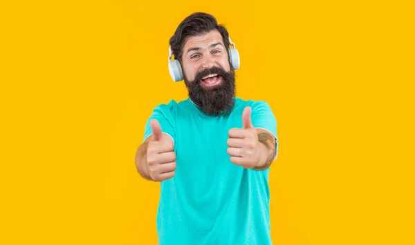 现代人的装置能显示大拇指 在耳机里听音乐的嬉皮士被黄色隔离了 戴嬉皮士耳机听音乐的家伙 工作室拍摄的嬉皮士家伙与耳机 听音乐 — 图库照片