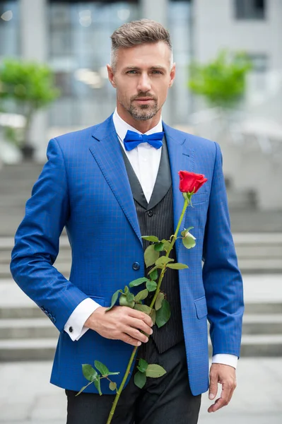 elegant man in tuxedo at romantic occasion. man with romantic present. handsome romantic man with present.