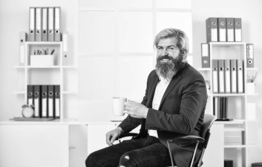 Çay zamanı. İçgüdülerine güvenmelisin. Sakin ol ve sakin ol. Kahve iç. Sakallı adam sıcak içecek içiyor. İş adamı ofiste kahve içer. Kahvaltılık çay. Sabah içeceği. Keyif.