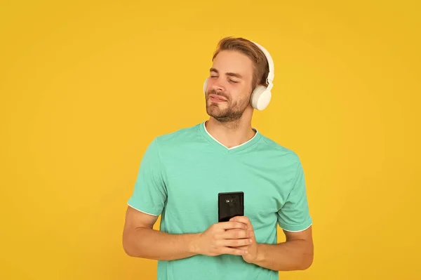 幸せな若い男は ヘッドフォンと携帯電話で音楽を聴くのを楽しむ黄色の背景 レジャー — ストック写真