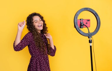 Mutlu çocuk uzun kıvırcık saçlarıyla blogda video çekerken iyi eğlenceler..