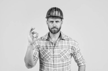 Adam işçi üniforması giyiyor. Kasklı yakışıklı bir müteahhit. Olgun adam kareli gömlek giyer. Profesyonel inşaatçı ya da tamirci. İnşaat mühendisi, iyi niyet göstergesi. Ciddi görünüşlü bir mimar..