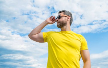 guy wearing yellow shirt and sunglasses outdoor on sky background.