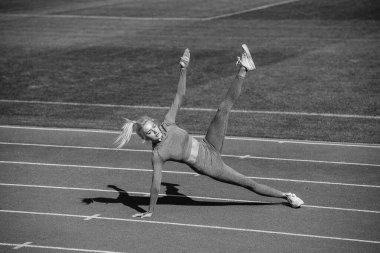Spor salonundaki atletik kadın stadyumda geriniyor, yoga yapıyor..