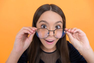 Sarı arka planda uzun saçlı ve gözlüklü, zeki bir kız çocuğu. Sürpriz..