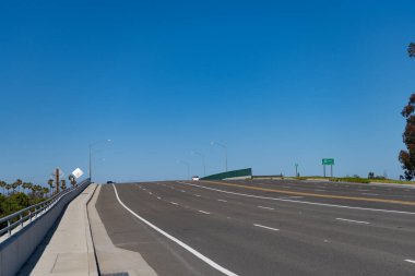 Mavi gökyüzü arka planında ufuk çizgisi görünümlü boş yol.