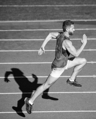 Enerjik atletik kaslı koşucu dışarıda stadyumdaki hipodromda koşuyor, dayanıklı..