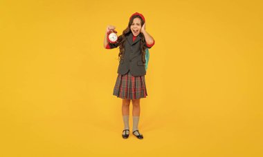 Çalar saati olan bağıran bir çocuk. Genç kız sırt çantası taşıyor. Okula dönüyorum. Bilgi günü. Eğitim zamanı. Sarı arka planda üniformalı bir çocuk. 1 Eylül. Mutlu çocukluk..