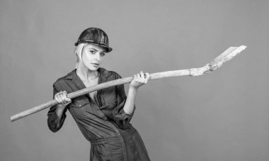 Koruyucu miğfer takan kadın mimar turuncu arka planda kürek tutuyor, mühendislik..