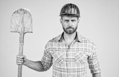 İnşaat kaskı ve kareli gömlekli yakışıklı işçi inşaat alanında kürekle, sanayiyle....