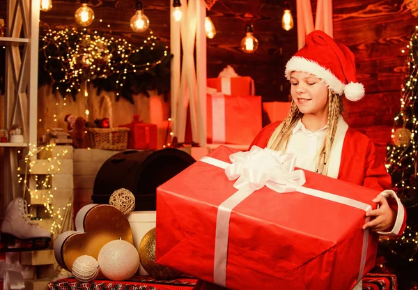 魔法の喜び今の箱の子だ冬の買い物販売 クリスマスツリーの陽気な女の子喜びで家を飾る クリスマス気分だ家族の休日のお祝い新年明けましておめでとう赤いサンタの帽子の子供は — ストック写真