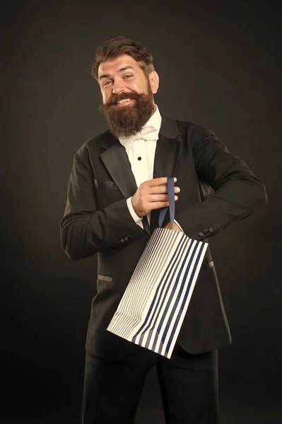 タキシード ボウのネクタイ姿の幸せな男が買い物袋を背景に黒い服を着ている 誕生日 — ストック写真